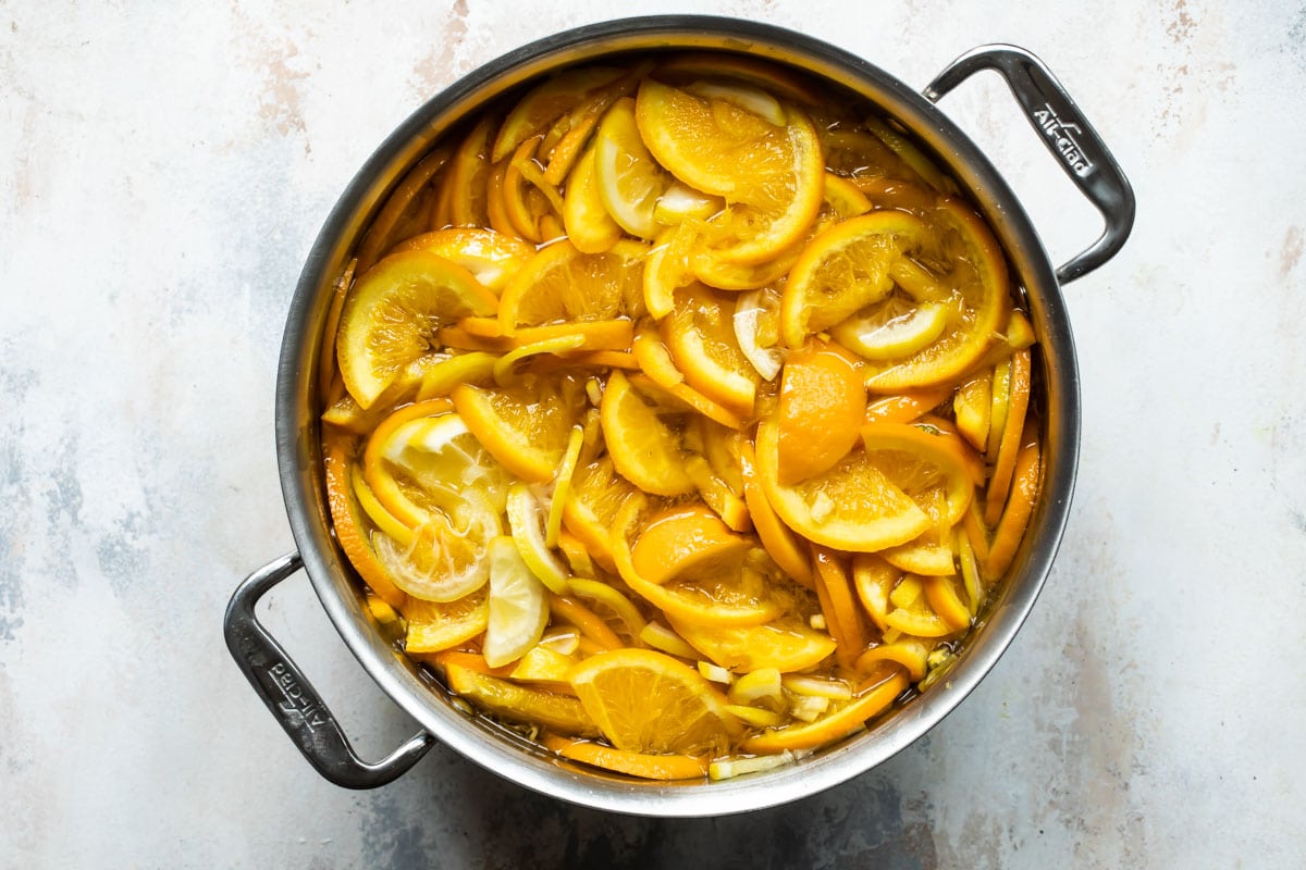 A pot full or orange and lemon slices for orange marmalade.
