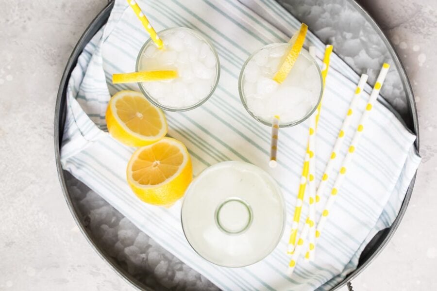 An overhead shot of how to make lemonade in glasses on a silver platter.