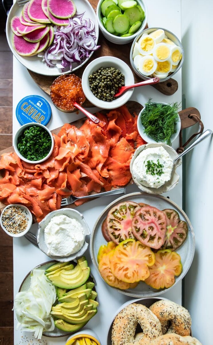 A Bagel Bar stocked with bagels, smoked salmon, cream cheese, avocado, tomatoes, watermelon radishes, cucumbers, caviar, and fresh herbs and spices.