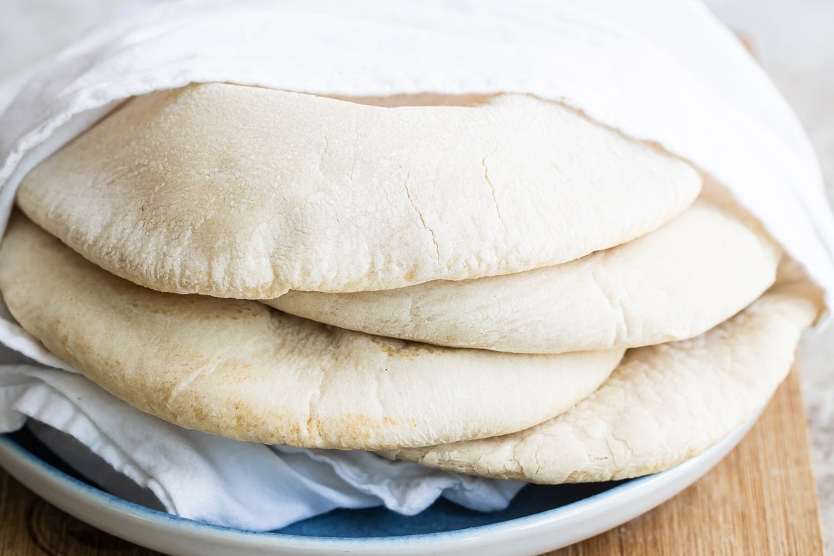 A stack of pita breads wrapped in a towel.