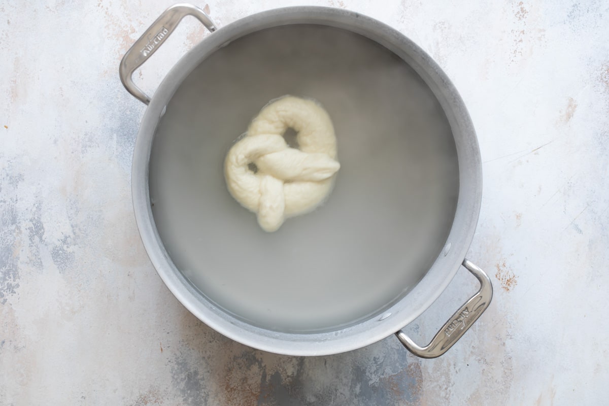 A homemade soft pretzel in boiling water.