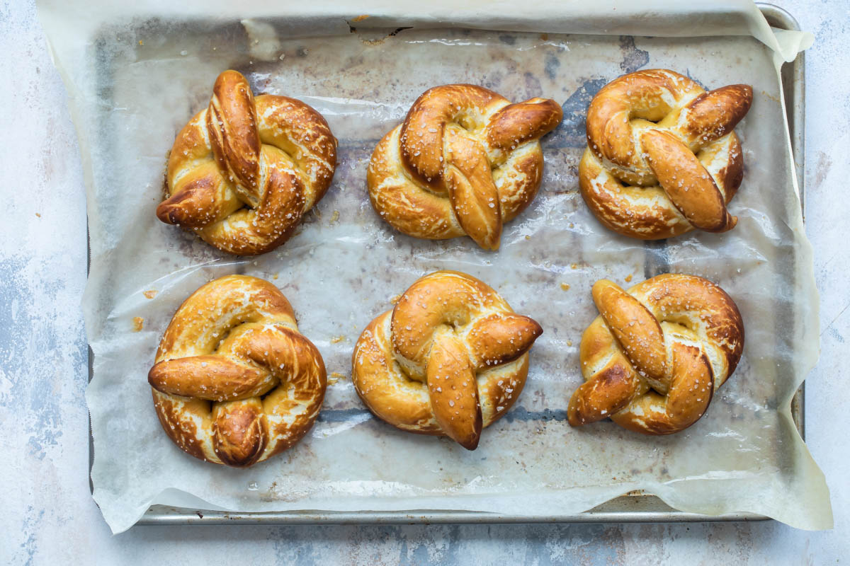 Homemade soft pretzels on a baking sheet.