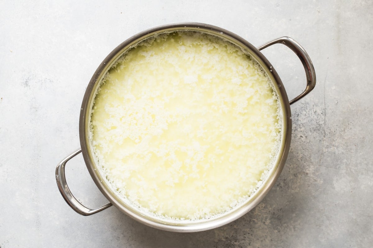 Ricotta cheese being made in a silver pan.