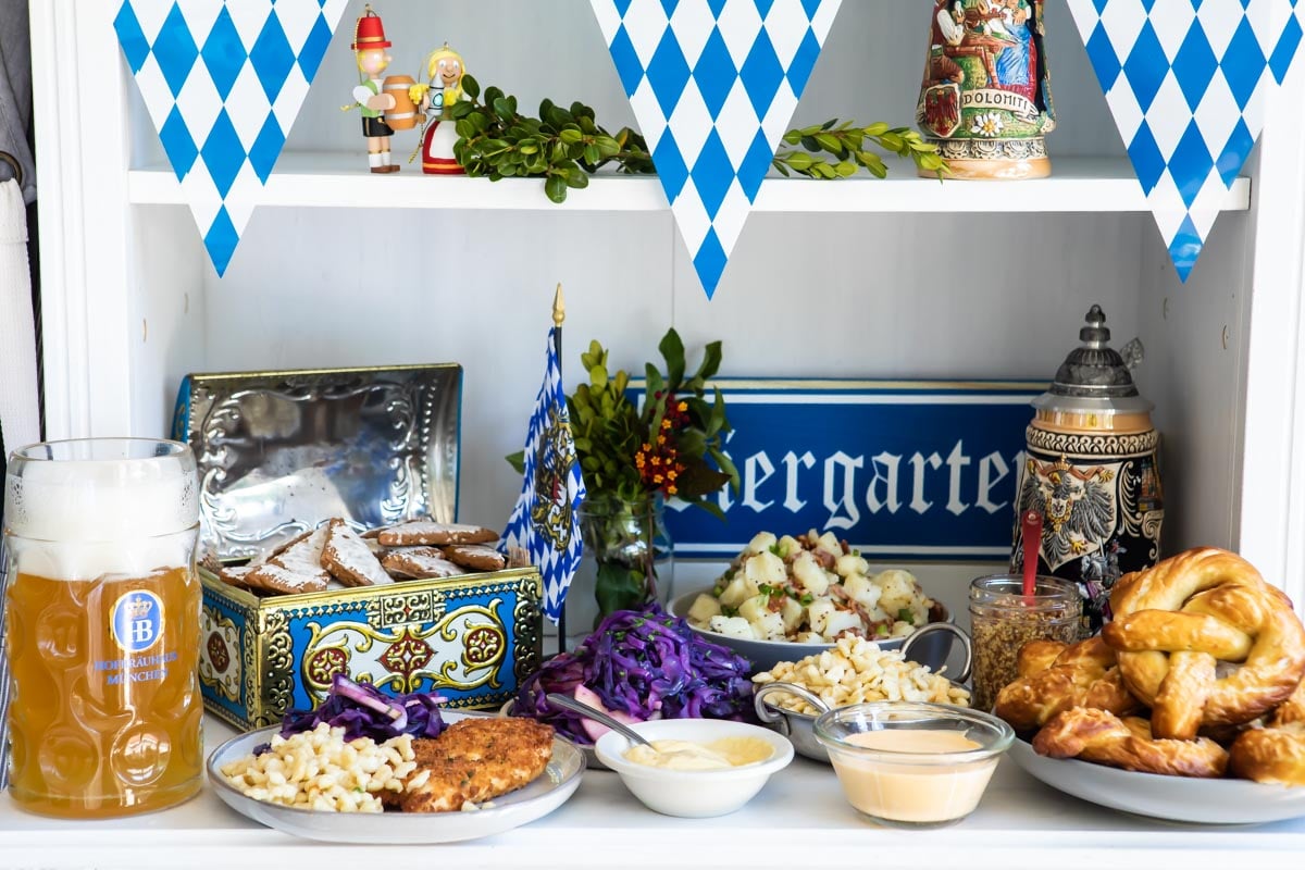 A table of Oktoberfest food including schnitzel, spaetzle, soft pretzels, German potato salad, Lebkuchen, and beer.