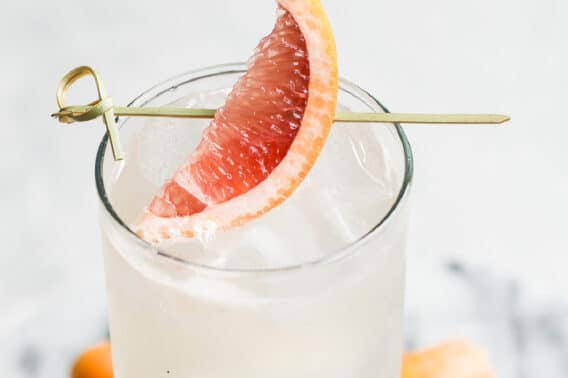 A collins glass with a Paloma cocktail in it, garnished with a grapefruit wedge.