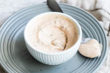 A bowl of remoulade sauce with a spoon next to it.