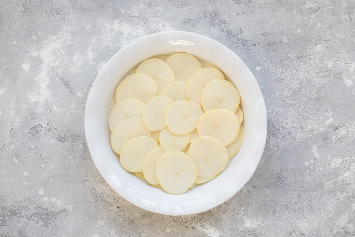 Buildlng scalloped potatoes in a white baking dish.