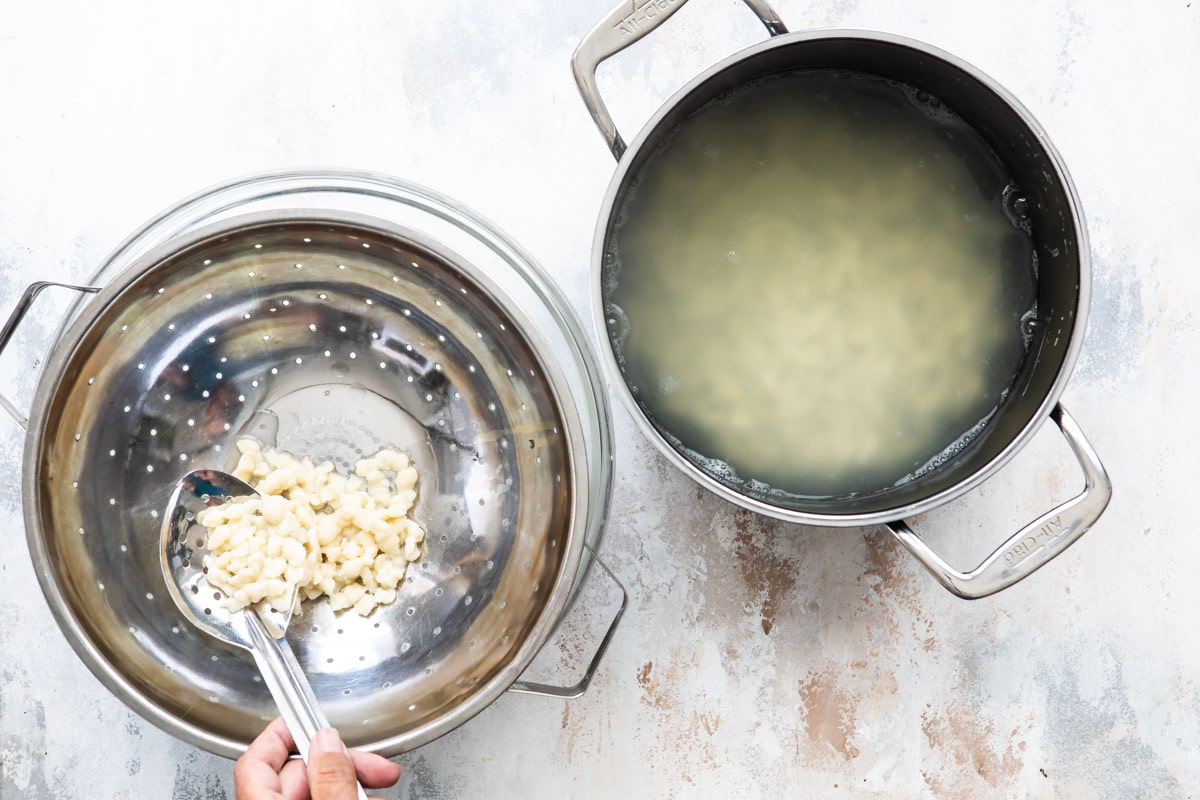 Draining boiled spaetzle in a colander.
