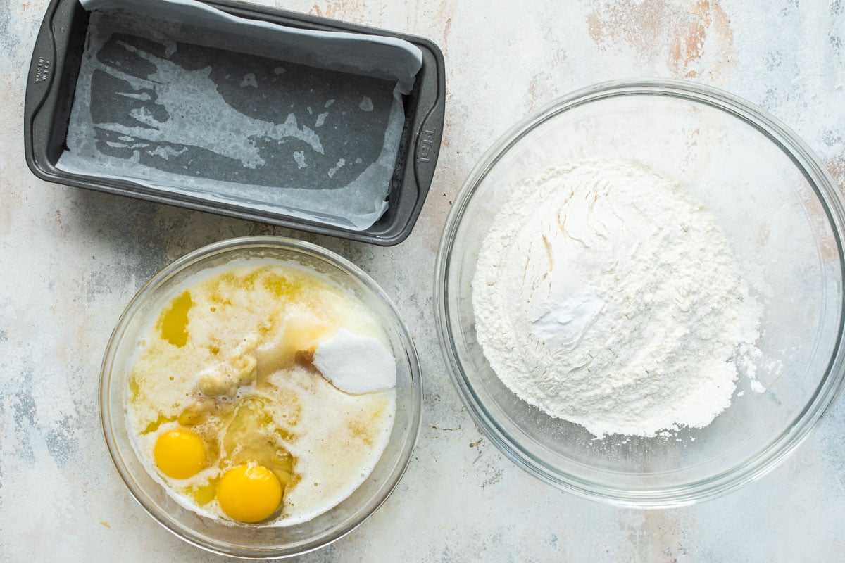 A bowl of wet ingredients next to a bowl of dry ingredients needed for banana bread.