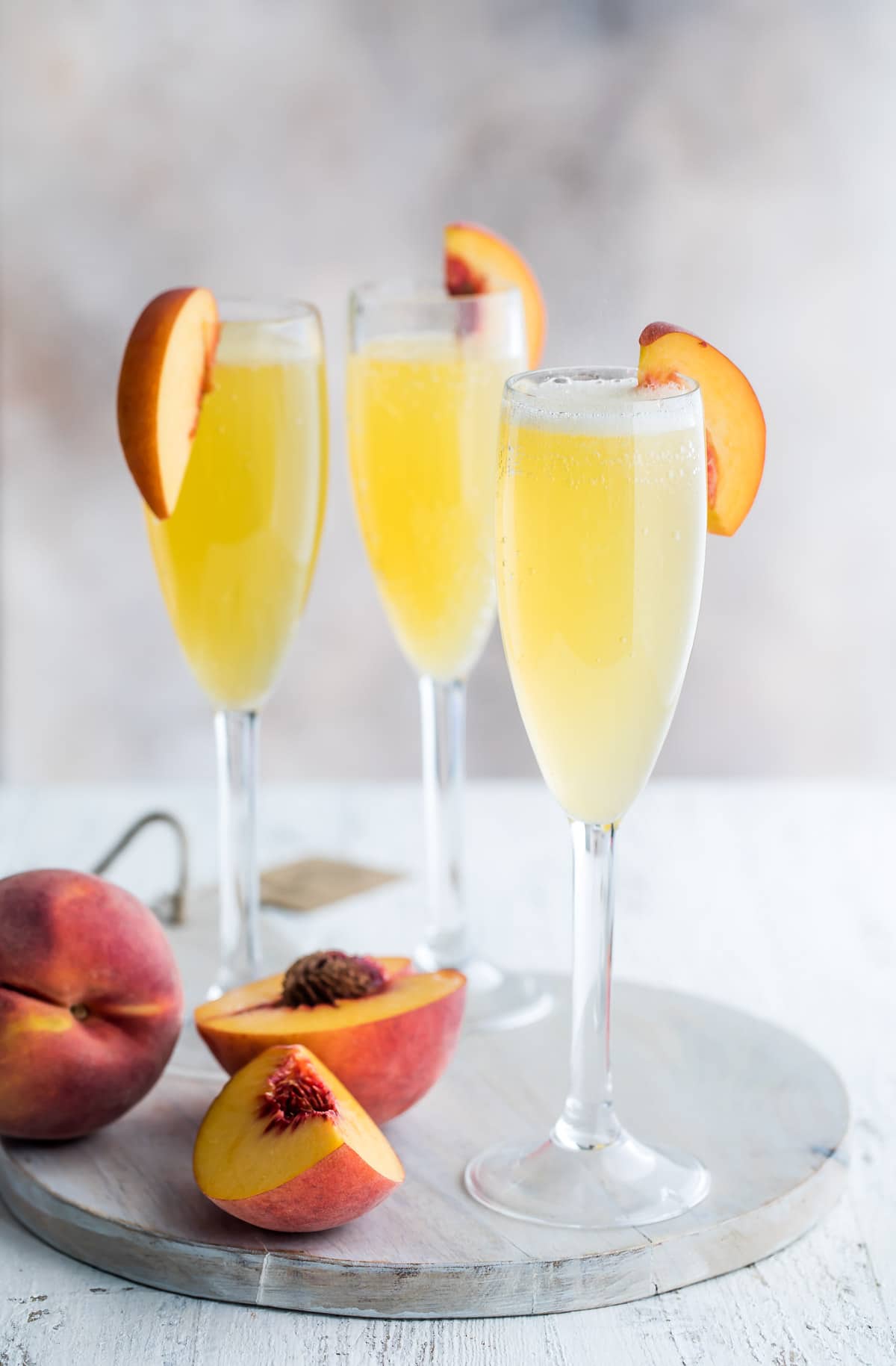 Three bellinis garnished with fresh peace slices.
