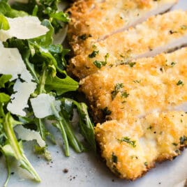 Chicken Milanese on a gray plate with a side of greens.