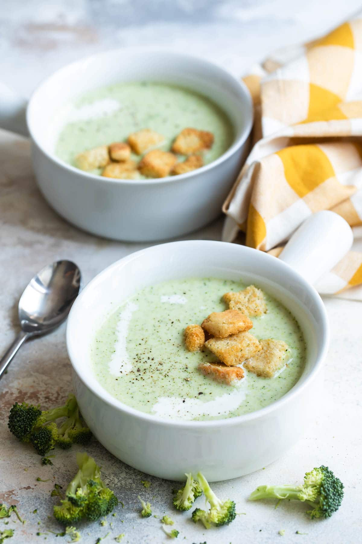Cream of broccoli soup in two handled bowls.