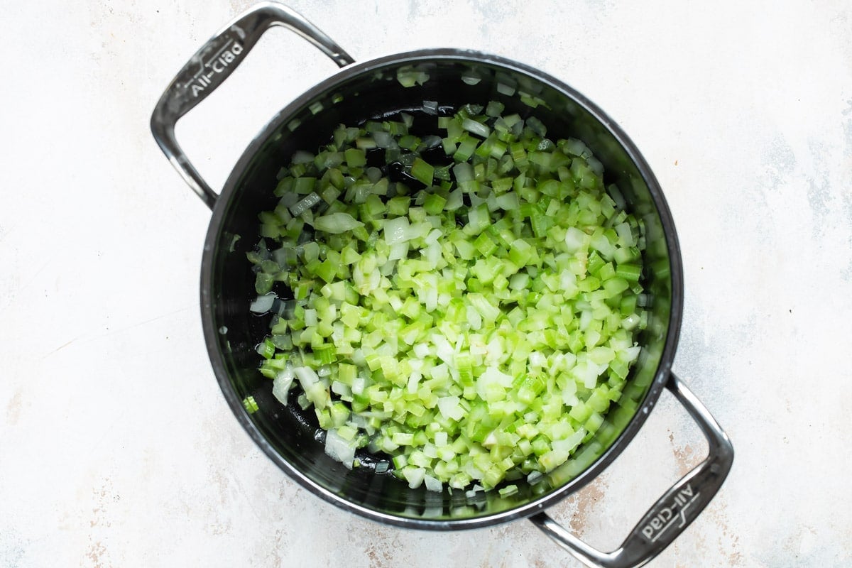 Celery and onion in a silver stock pot.