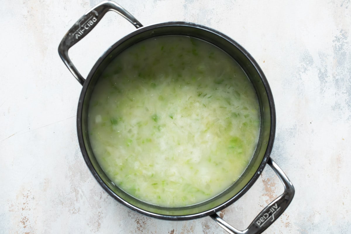 Celery, onion and water in a silver stockpot.