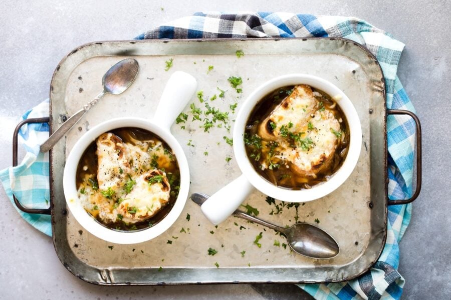 French onion soup in white bowls on a silver tray.