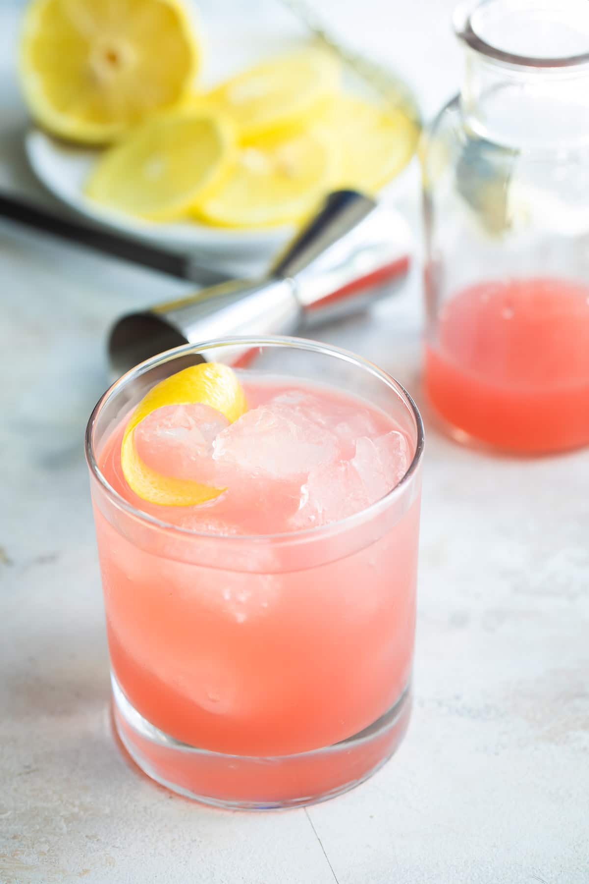 A Greyhound cocktail next to a carafe of grapefruit juice.