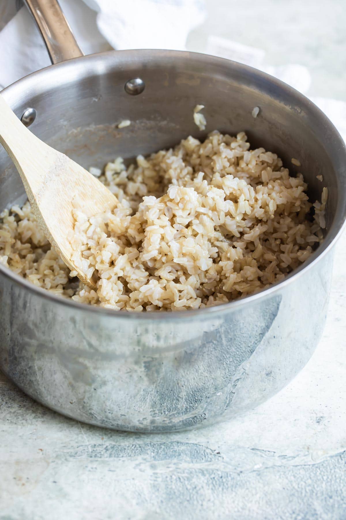 A pot of brown rice with a wooden spoon resting in it.