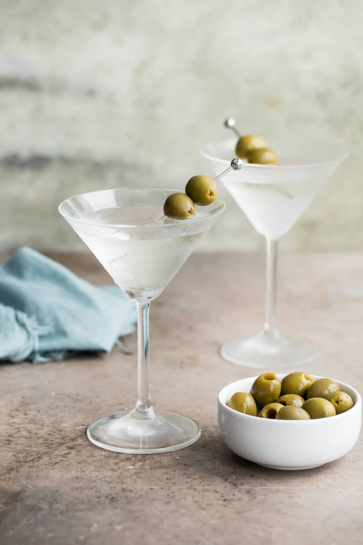 Two dry martinis garnished with green olives.