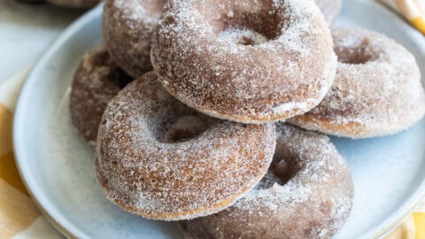 Seven apple cider donuts on a gray round plate.