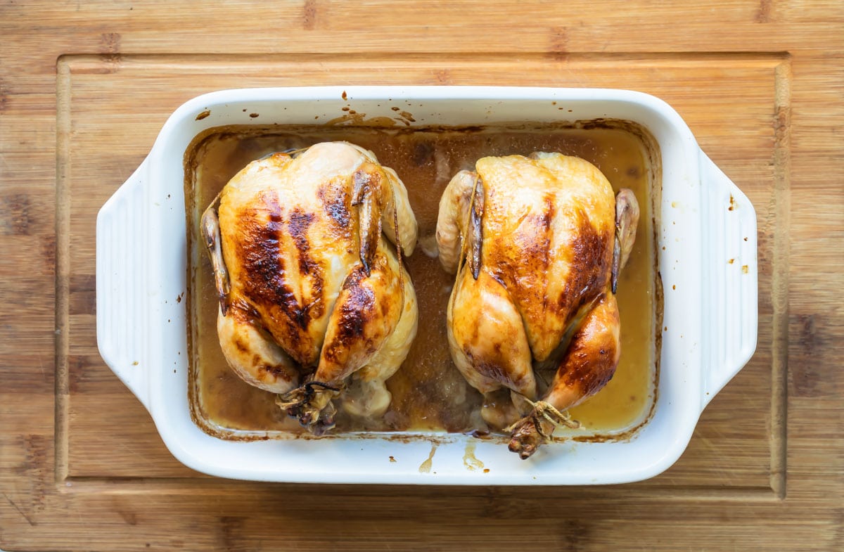 A pair of roasted Cornish hens in a baking dish.