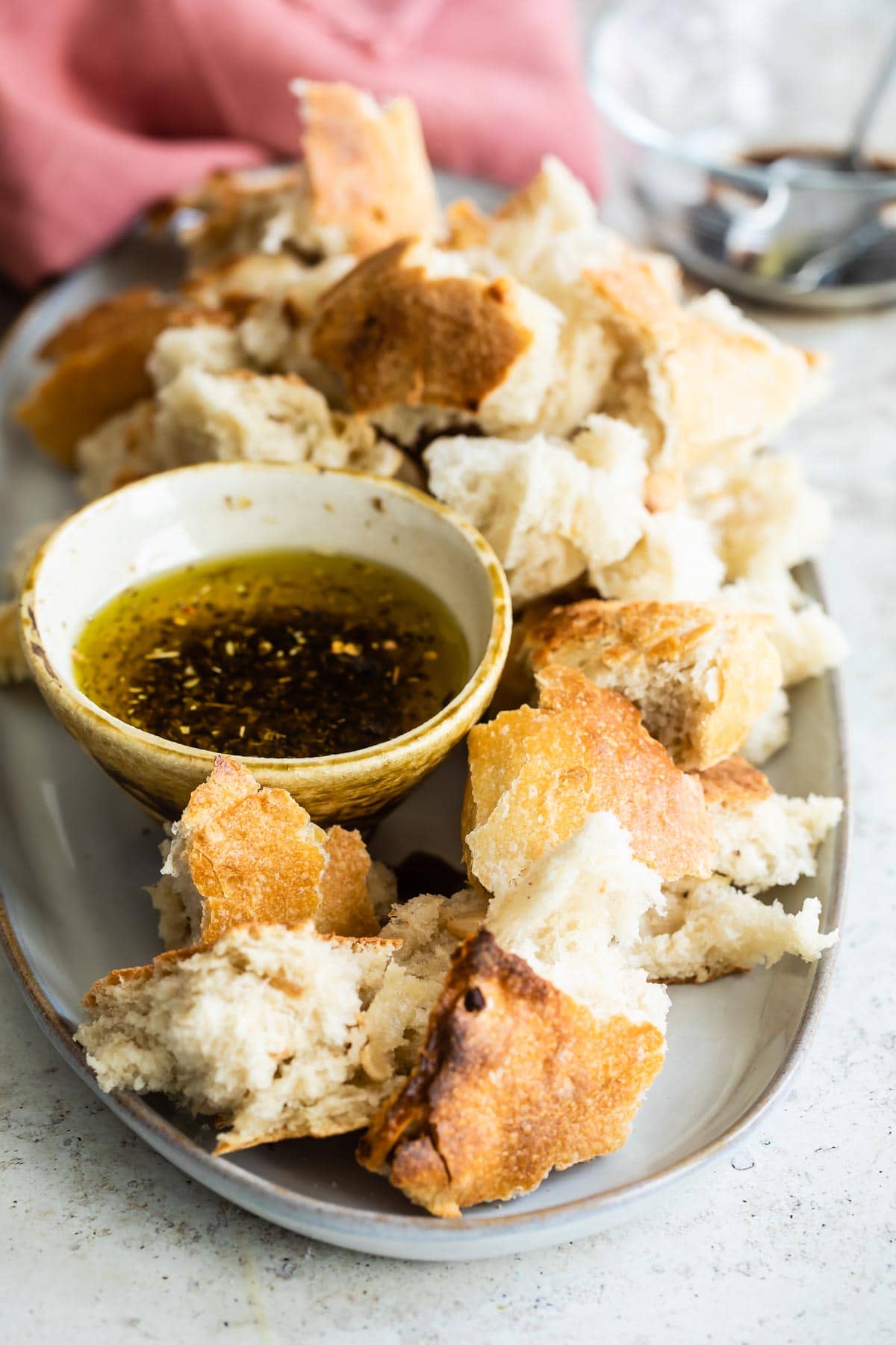 Ripped pieces of bread on a platter with dipping oil in a bowl.