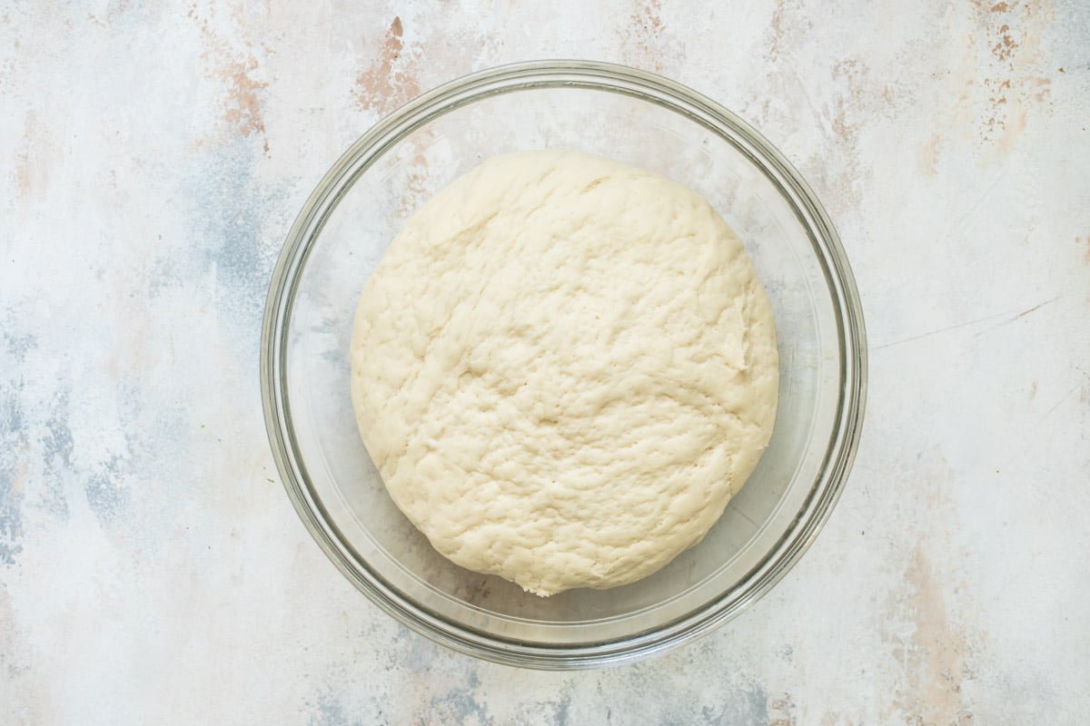 Homemade pita bread dough in a glass bowl.