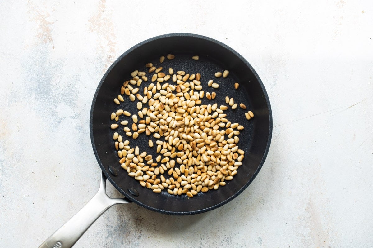 Toasted pine nuts on a skillet.