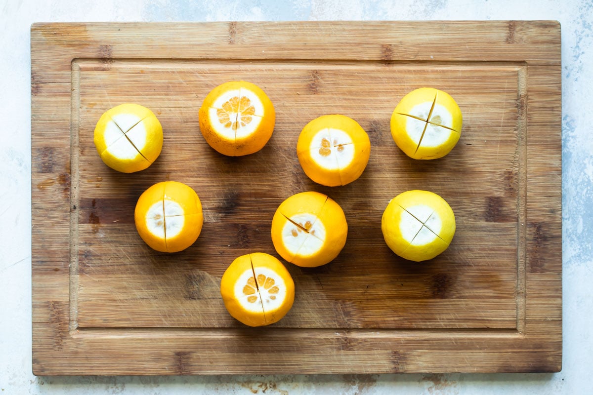 Quartered lemons on a wood cutting board.