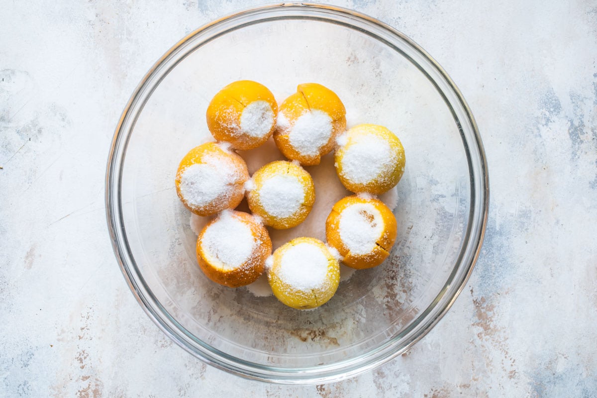 Quartered lemons with sugar in a glass bowl.