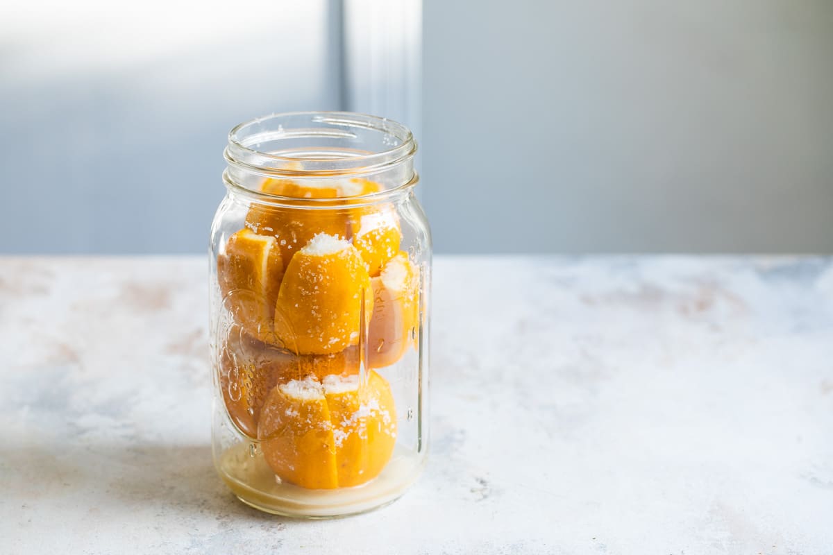 Quartered lemons and sugar in a clear mason jar.