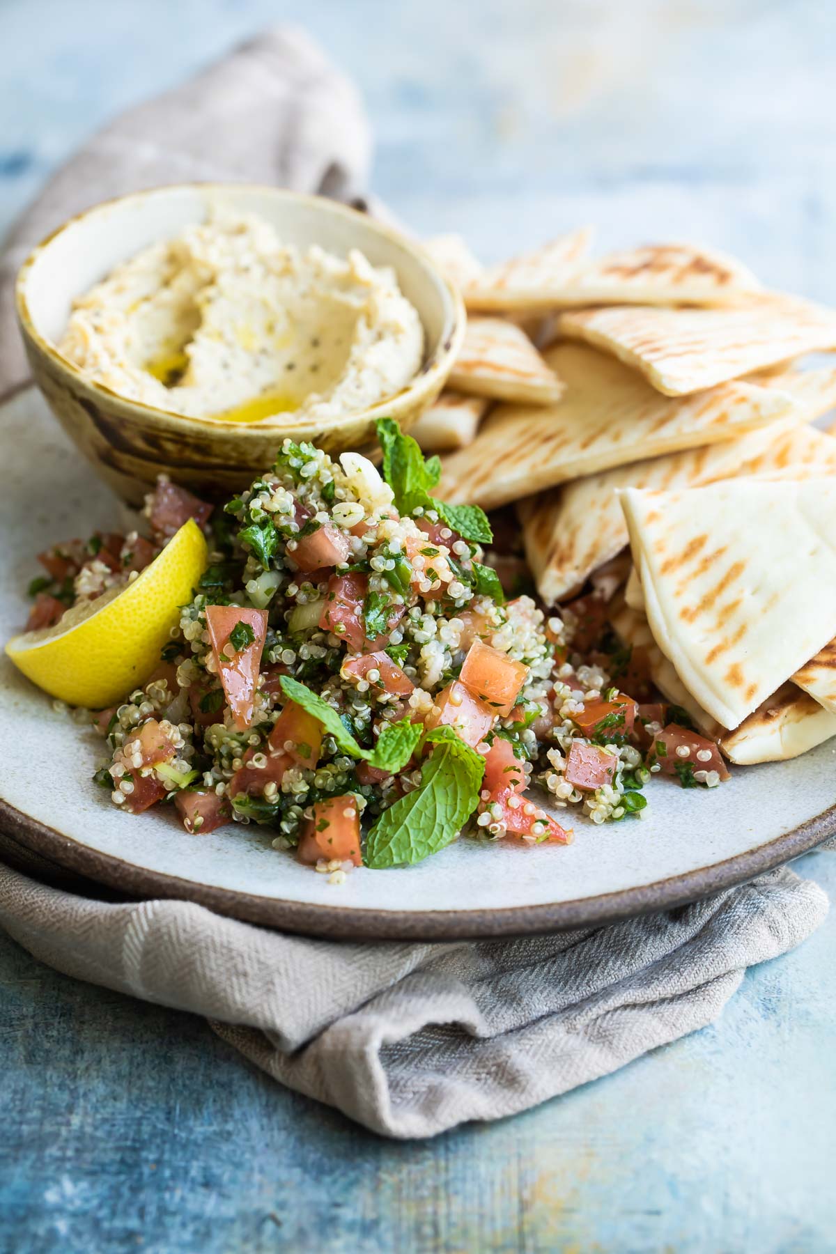 Quinoa tabbouleh on a plate with a side of hummus and pita triangles.
