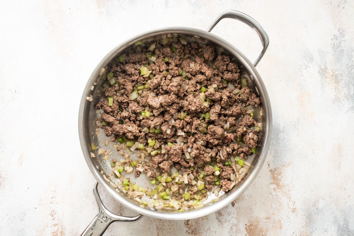 Overhead shot of ground beef and chopped vegetables in a silver skillet.