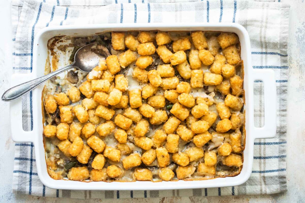 Overhead shot of tater tot casserole in a rectangular casserole dish with a helping scooped out.