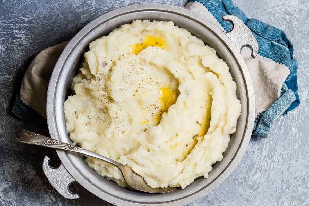 A metal serving dish full of the absolute best mashed potatoes.