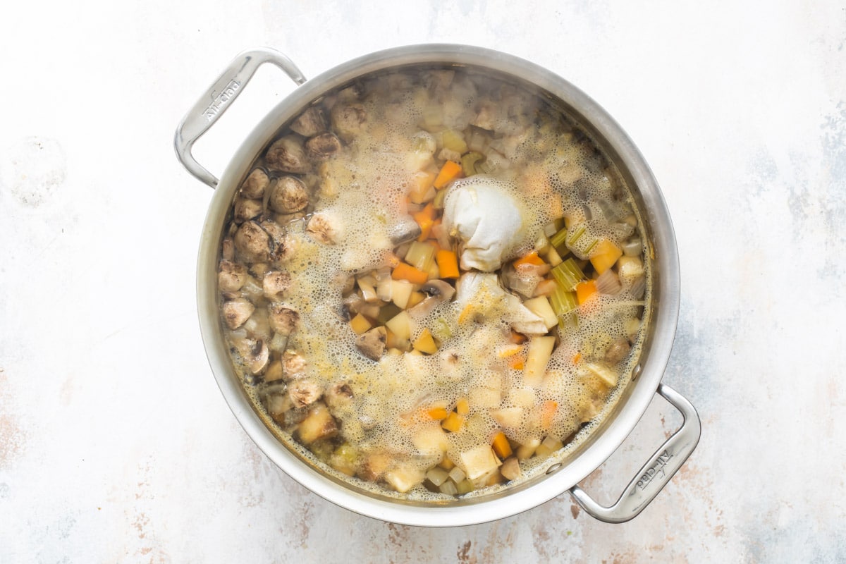 Boiling vegetables in stock in a silver pot.