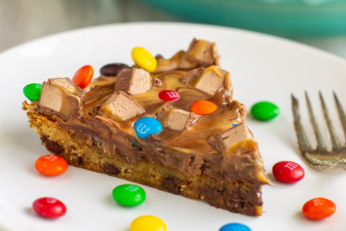 A chocolate chip cookie cake with a peanut butter swirl topping and chopped candy on top.