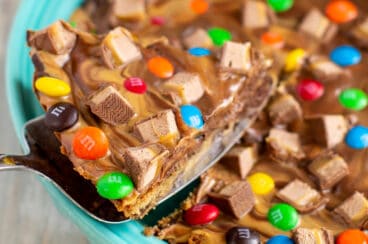 A chocolate chip cookie cake with a peanut butter swirl topping and chopped candy on top.