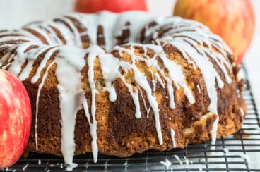 Cinnamon Apple Cake on a cooling rack surrounded by apples.