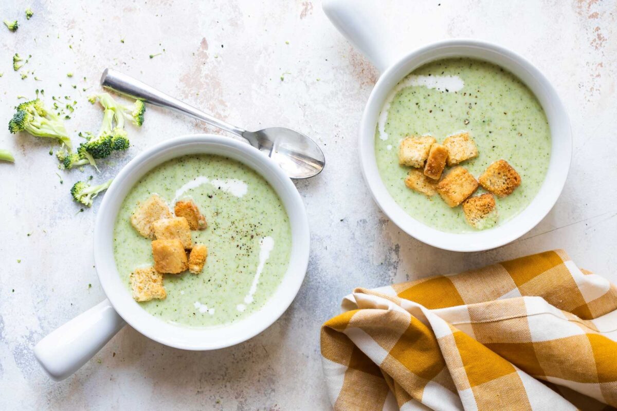 Cream of broccoli soup in two handled bowls.