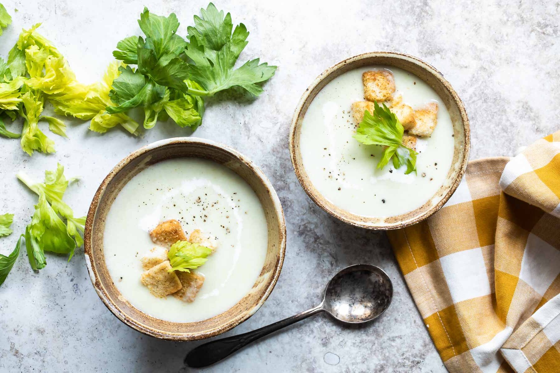 Cream of celery soup in two brown bowls.