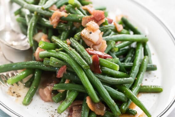 Green beans with bacon on a white platter.