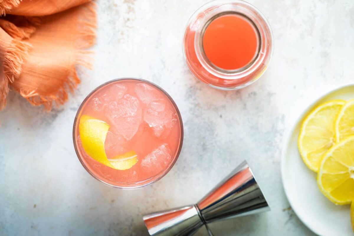 A Greyhound cocktail next to a carafe of grapefruit juice.