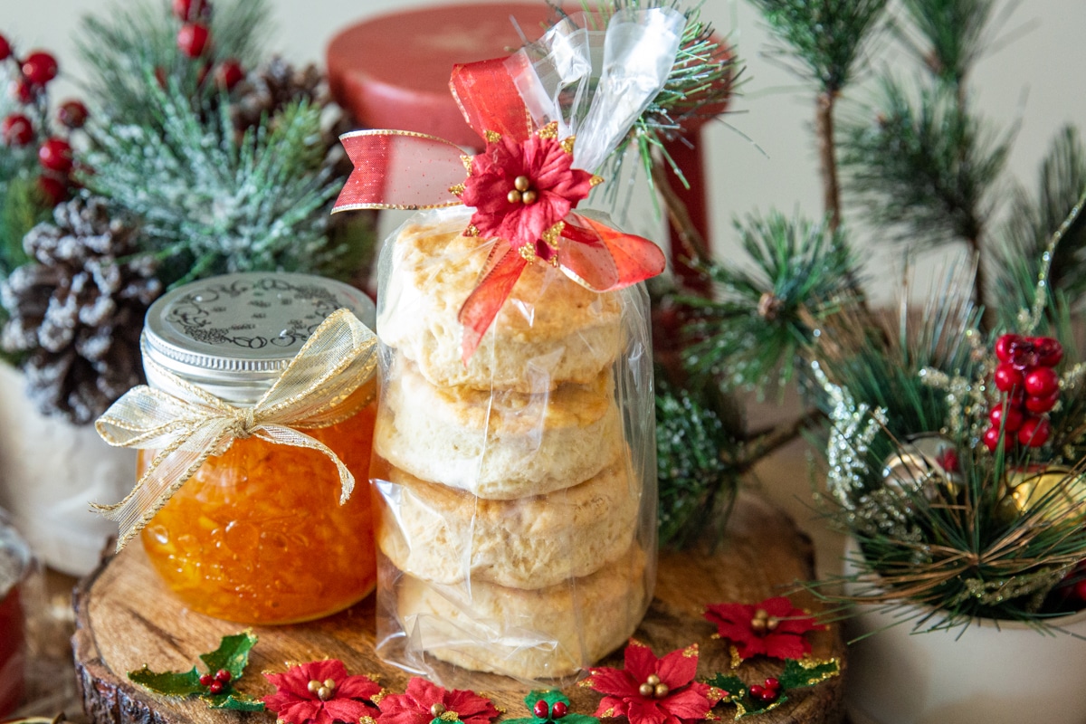 A jar of orange marmalade with a stack of biscuits, both wrapped as Christmas gift.