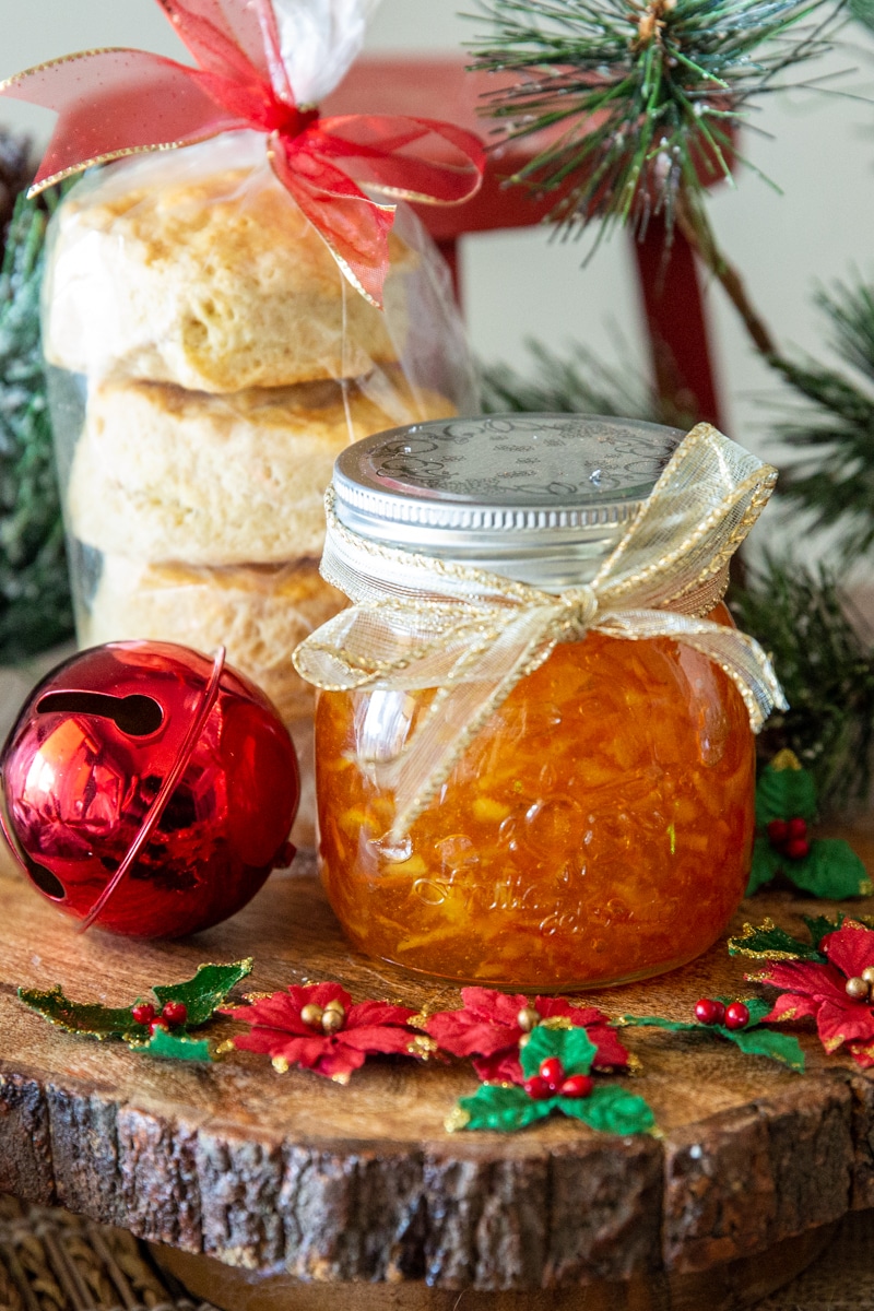 A jar of orange marmalade with a stack of biscuits, both wrapped as Christmas gift.