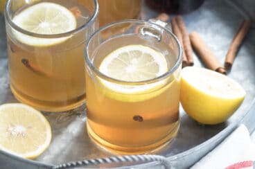 Hot toddy in clear mugs on a silver tray.
