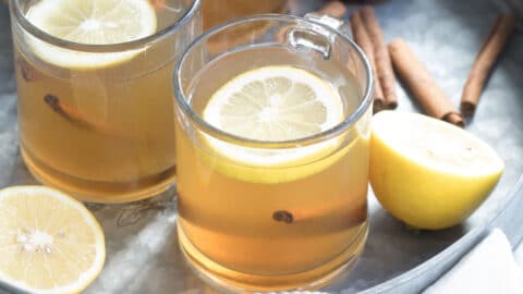 Hot toddy in clear mugs on a silver tray.
