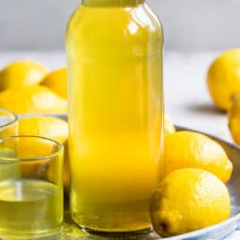 Limoncello in a bottle surrounded by lemons.