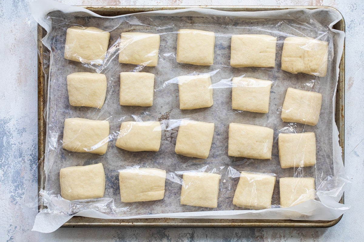 Squares of beignet dough on a baking sheet.