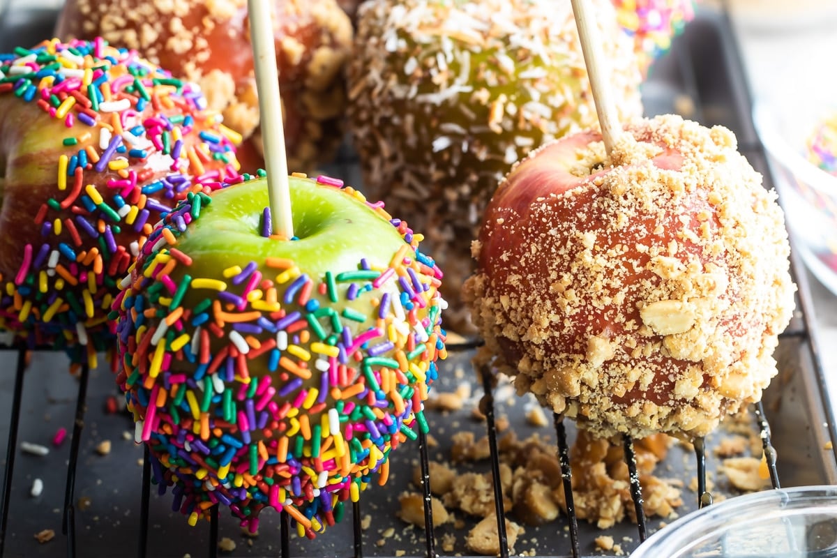 Decorated caramel apples on a cooling rack.