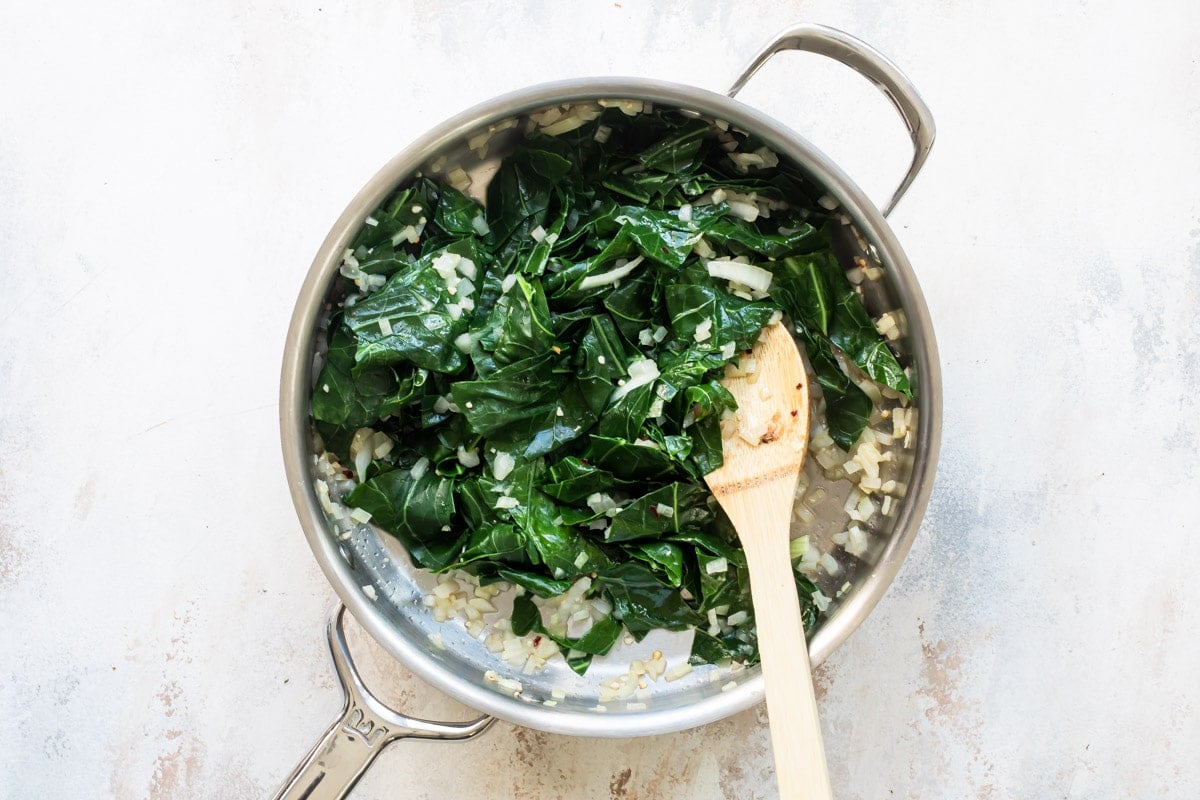 A skillet with cooked collard grees and onions.